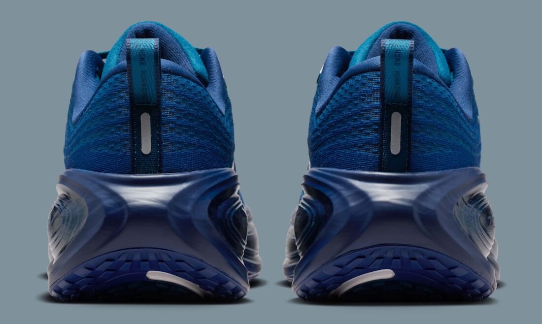 Image de la Nike Vomero Plus Swarovski Blue Force, sneaker en mesh bleu avec empiècements métallisés et cristaux Swarovski sur le Swoosh et les panneaux latéraux. Vue sur l'arrière de la paire. 