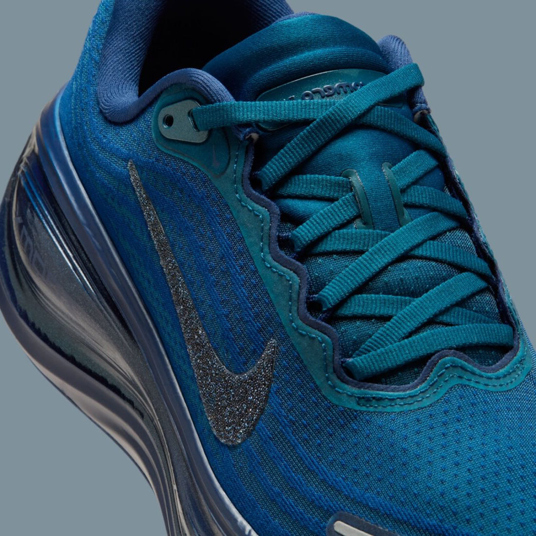 Image de la Nike Vomero Plus Swarovski Blue Force, sneaker en mesh bleu avec empiècements métallisés et cristaux Swarovski sur le Swoosh et les panneaux latéraux. Vue zoomée sur le profil de la paire. 