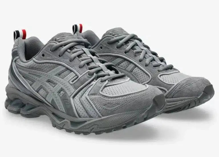 Sneakers ASICS Gel-Kayano 14 Thom Browne Grey en mesh gris et cuir premium avec technologie GEL™ et détails tricolores signature vue de 3/4 face. 