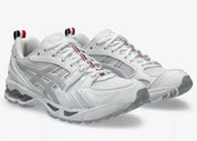 Sneakers ASICS Gel-Kayano 14 Thom Browne White en mesh blanc et cuir premium avec technologie GEL™ et détails tricolores signature vue de 3/4 face. 