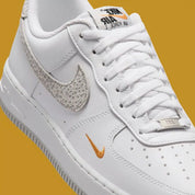 Vue zoomée sur les détails latéraux de la Nike Air Force 1 Low '07 White Kumquat Grey Fog, sneaker Nike blanche et grise avec détails orange Kumquat, Swoosh latéral et amorti Nike Air.